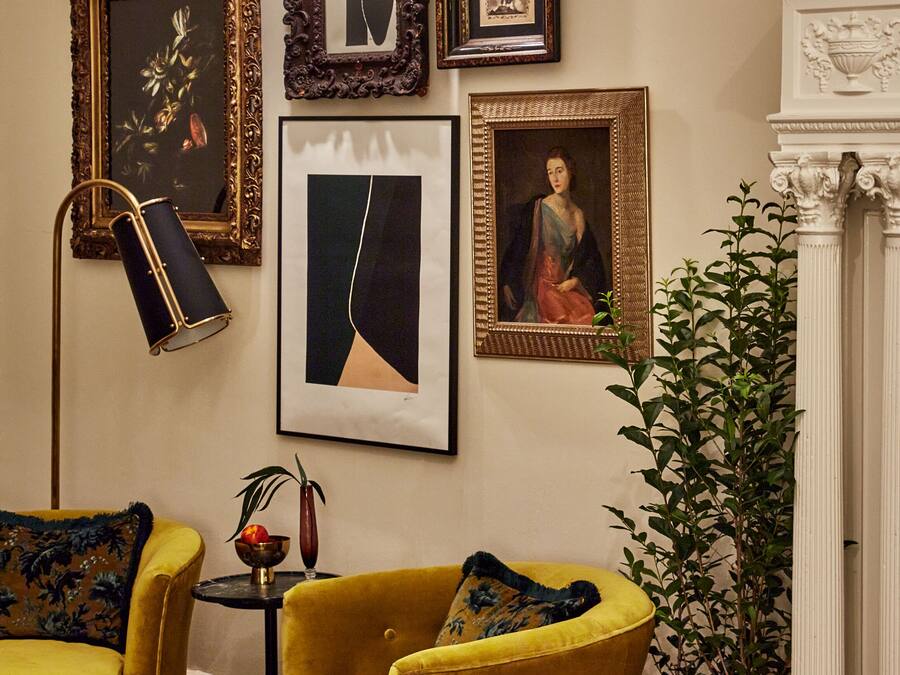 Une pièce avec un fauteuil jaune, un lampadaire et une cheminée.
