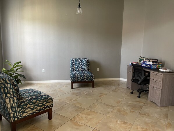 A room with a patterned armchair, a matching chair, a desk with boxes, and a potted plant. - Serendipity Place Inverness w/ private pool (Inverness)