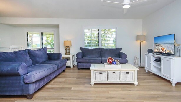 A living room with two sofas, a coffee table, a TV, and a ceiling fan.