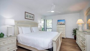 A bedroom with a bed, nightstands, a dresser, a ceiling fan, and a window with blinds.