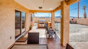 Une terrasse couverte équipée d’un barbecue, d’un coin salon et offrant une vue sur le paysage environnant.