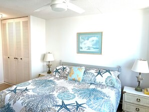 A bedroom with a bed, two nightstands, a star-shaped lamp, a framed picture, and a ceiling fan.
