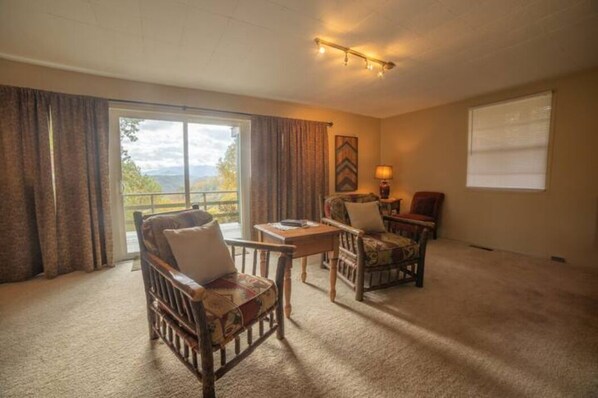 A spacious room with a large window, a wooden chair, a small table, and a lamp. - THE HEAD REST at Deals Gap, Tail of the Dragon Mountain Retreat! (Robbinsville)