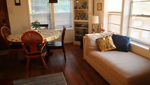 A cozy living room with a sofa, a dining table with chairs, and a bookshelf.