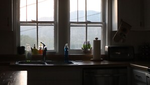 A kitchen with a window, a sink, a microwave, and a toaster.