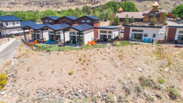 Un edificio moderno con varias unidades, un espacio exterior cubierto y un paisaje montañoso al fondo.