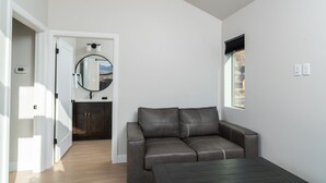 Ett modernt vardagsrum med en soffa i läder, ett soffbord och utsikt över en stadssiluett genom ett fönster.