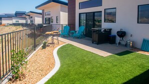 Een modern terras buiten met een barbecue, zithoek en uitzicht op het omliggende landschap.