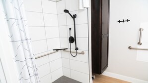 Un área de ducha con ducha de mano y panel de control.