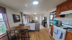 A kitchen with wooden flooring, a dining area with stools, a stove, and wooden cabinets. - Cozy Cabin lake front (Dalbo)