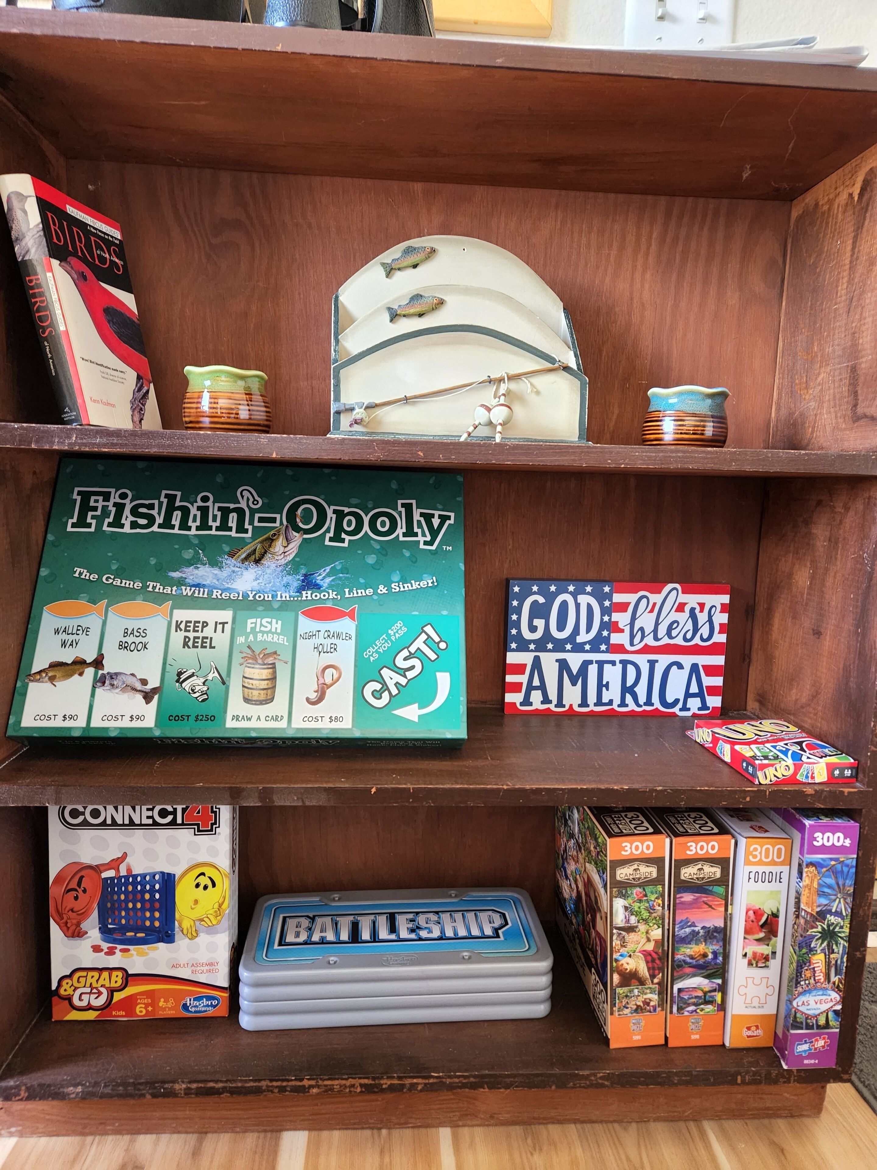 A wooden shelf with various board games and a fishing-themed game box.
