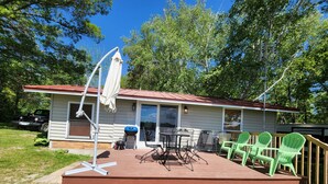 A house with a covered patio, outdoor seating, and a grill. - Cozy Cabin lake front (Dalbo)