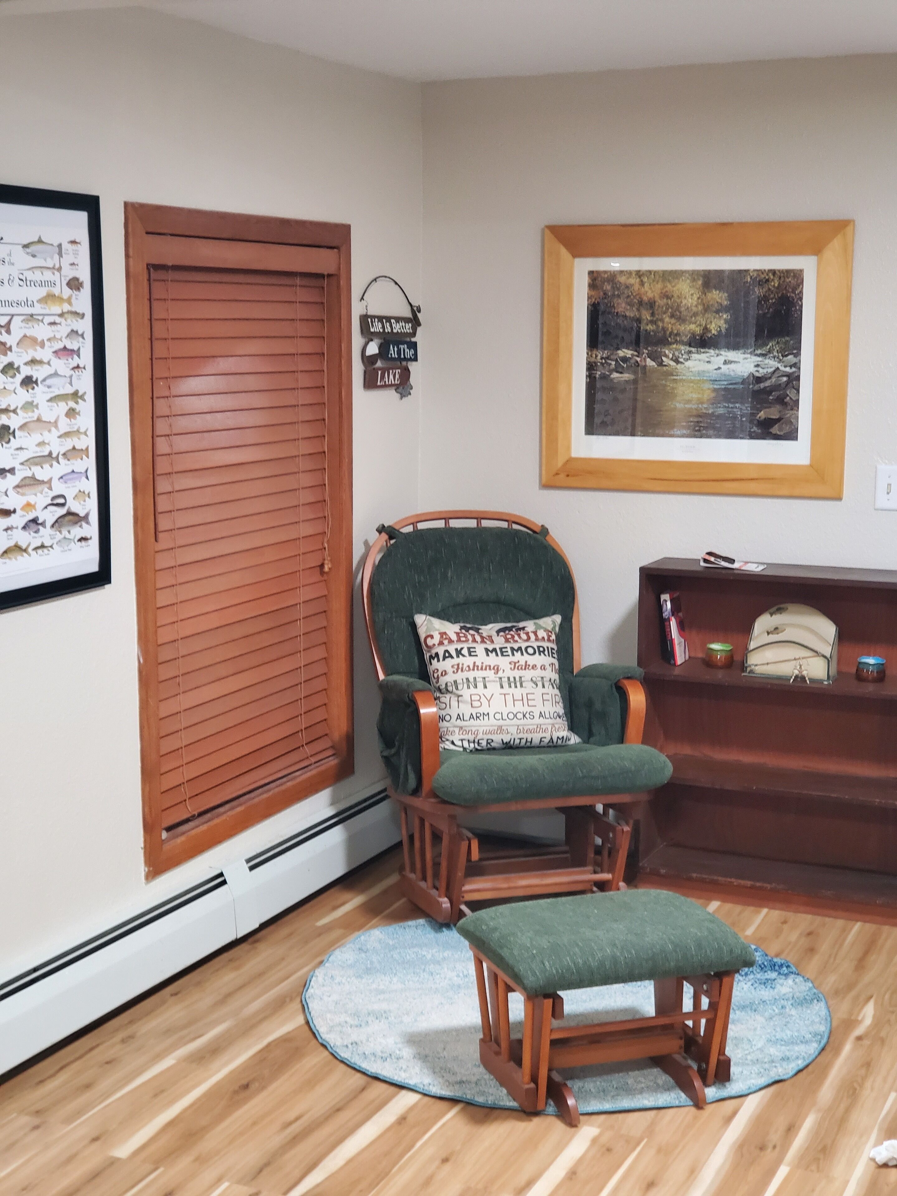 A room with a wooden chair, a framed picture on the wall, and a door with a sign.