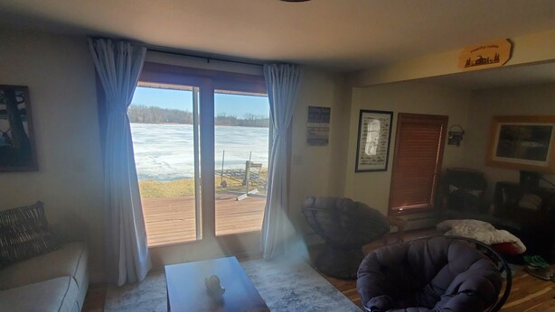 A living room with a large window, a sofa, a bean bag chair, and a coffee table. - Cozy Cabin lake front (Dalbo)