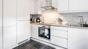 Eine moderne Küche mit weißen Schränken, einem Edelstahlbackofen und einer gefliesten Spritzschutzwand.