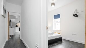 Ein Schlafzimmer mit einem Bett, einem Fenster und einer Tür, die in eine Küche führt.