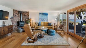 Una sala de estar moderna con chimenea de ladrillo, un ventanal con vistas y un rincón de asientos acogedor.