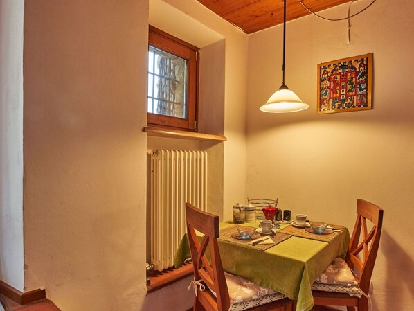 A dining area with a table set for two, a radiator, a window, and a hanging light fixture. - Cosy apartment in villa for 2 people with WIFI, TV and terrace (Caprino Veronese)