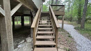 A wooden staircase leading to a wooden deck with a stone pathway.