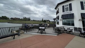 A waterfront restaurant with outdoor seating, a view of the water, and a sign reading "SEAFOOD".