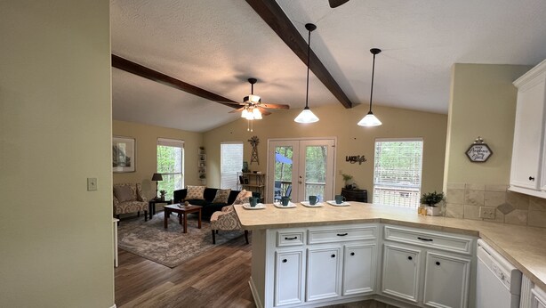 A kitchen with white cabinetry, a wooden ceiling, and pendant lights.