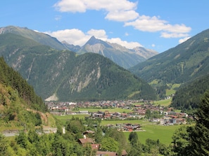A mountainous landscape with a valley town featuring houses and buildings, surrounded by lush greenery and mountains.