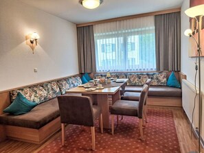 A dining area with a table set for four, surrounded by a sofa and chairs.
