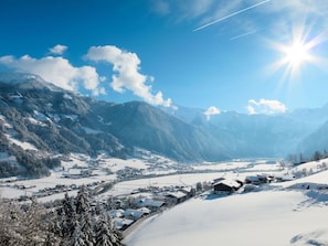 Uma aldeia nas montanhas coberta de neve, com casas tradicionais e um céu limpo.