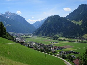 A valley with a small town nestled among green fields and mountains.