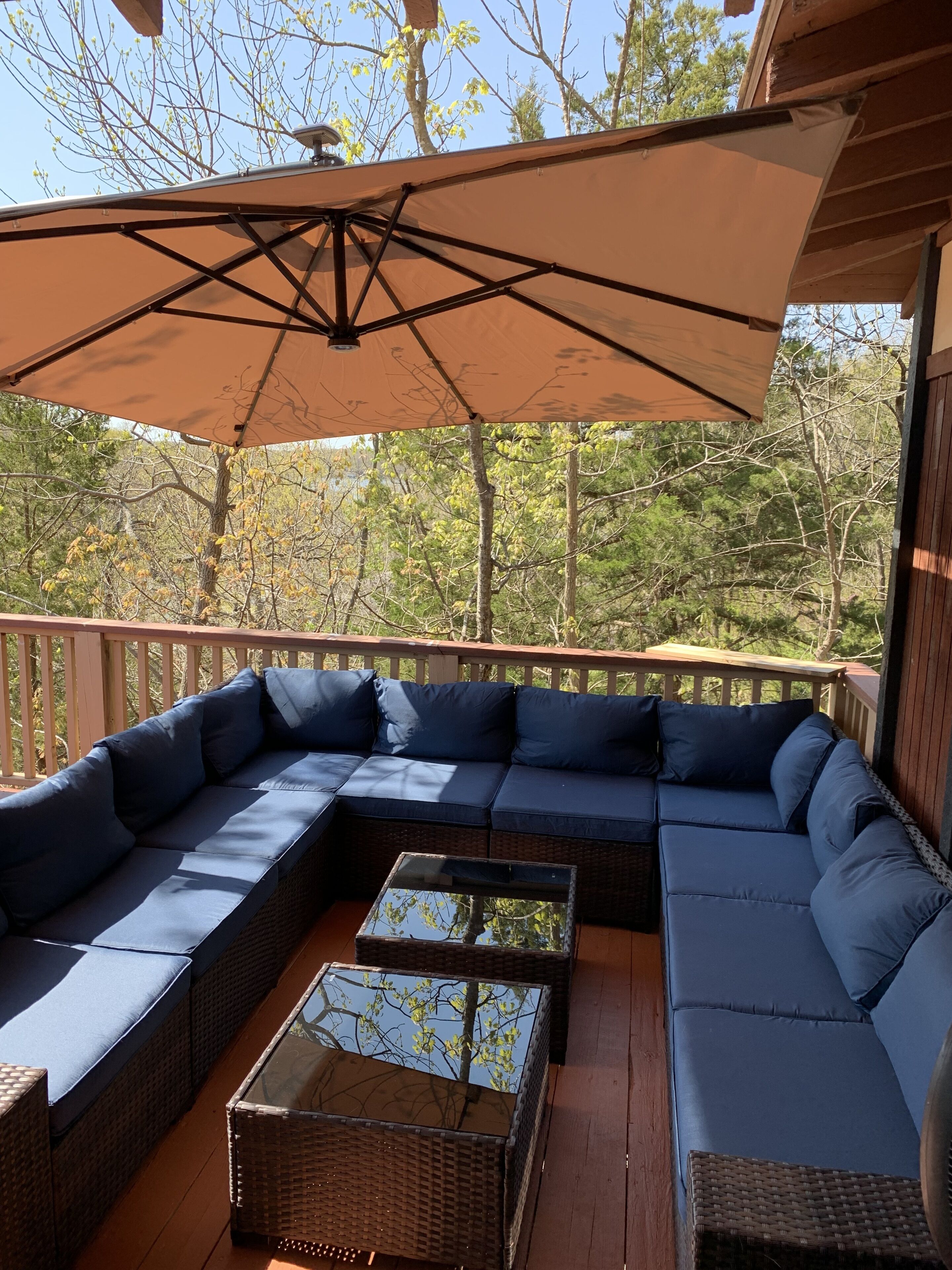 A covered outdoor seating area with a large sectional sofa and a glass-top coffee table.