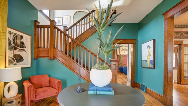 A room with a wooden staircase, a round table with a potted plant, a pink chair, and books. - ✨️Family Friendly Getaway✨️Small or Large Groups Welcome - Eclectic Design Gem! (Johnson City)