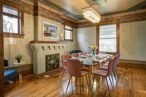 Un comedor con una mesa de madera, sillas rosas y un candelabro.