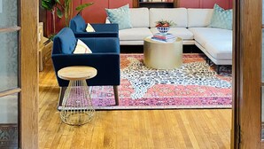 A living room with a blue sofa, a white sectional, a wooden coffee table, and a patterned rug. - ✨️Family Friendly Getaway✨️Small or Large Groups Welcome - Eclectic Design Gem! (Johnson City)
