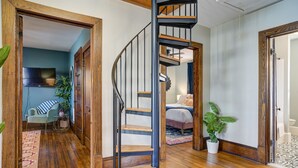 A spacious living area with a wooden staircase, a sofa, and a large potted plant. - ✨️Family Friendly Getaway✨️Small or Large Groups Welcome - Eclectic Design Gem! (Johnson City)