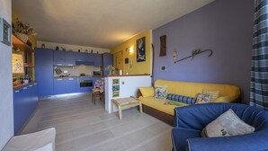 A compact living space with a kitchen, a sofa, and a dining area. - Rebecca's House among the greenery, Bardonecchia, Italy (Bardonecchia)