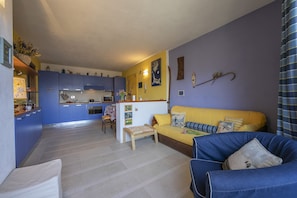 A compact living space with a kitchen, a sofa, and a dining area.