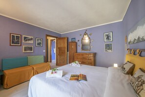 A bedroom with a bed, a sofa, a dresser, and a mirror.