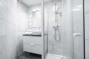 A modern bathroom with a glass-enclosed shower, a white sink, and a mirror above the counter. - Appartement Shakespeare, Nice, France (Nice)