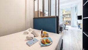 Une chambre d’hôtel avec un lit, des serviettes, des articles pour le petit-déjeuner, un livre et une vue sur l’extérieur.