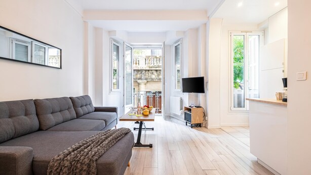 Un salon moderne comprenant un canapé, un téléviseur et un coin repas avec une table et des chaises.