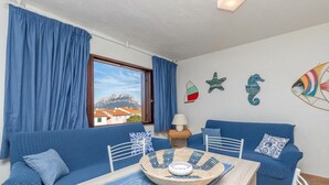 Una stanza con due divani blu, un tavolo in legno con un vassoio intrecciato, una lampada e decorazioni murali.