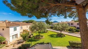 Un quartiere residenziale con vista libera su una casa con tetto in tegole, un prato curato e un albero grande in primo piano.