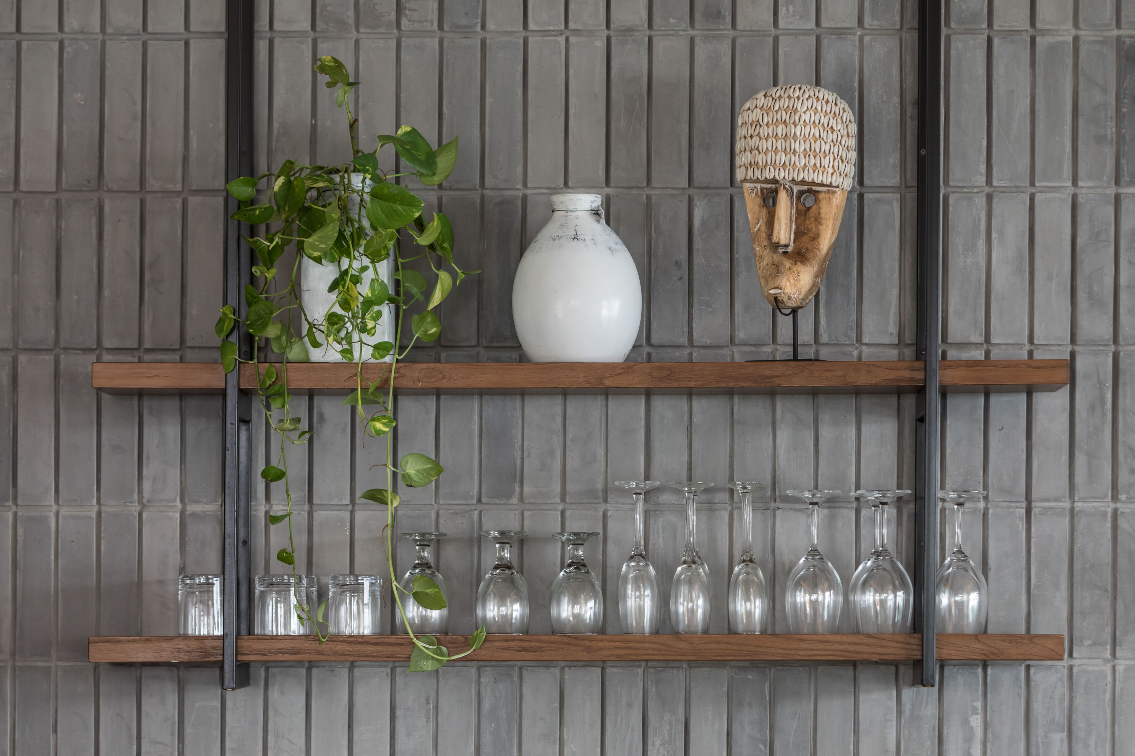 A wall with two wooden shelves holding various items.