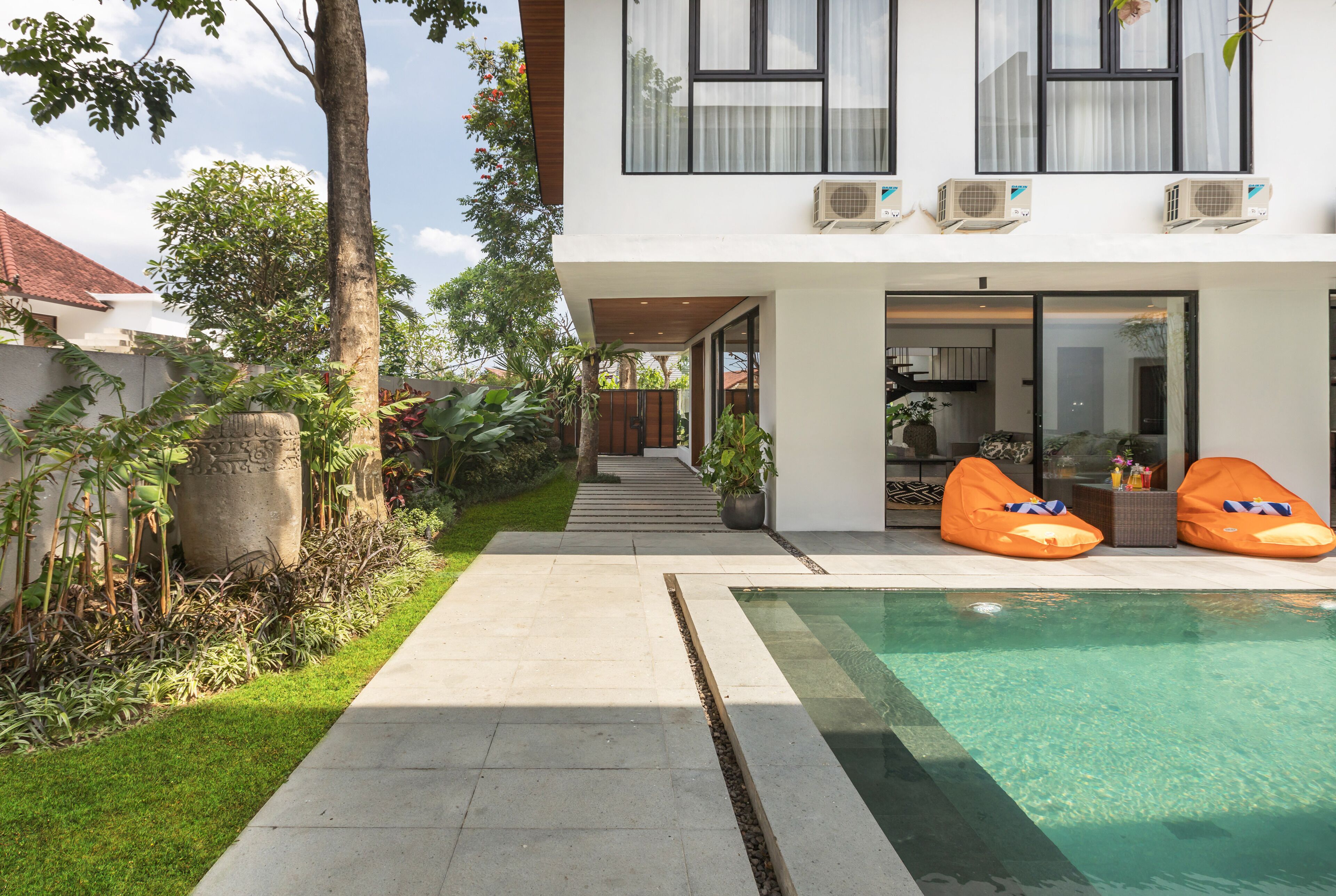 Una casa moderna con piscina, mobiliario de exterior y un jardín bien cuidado.