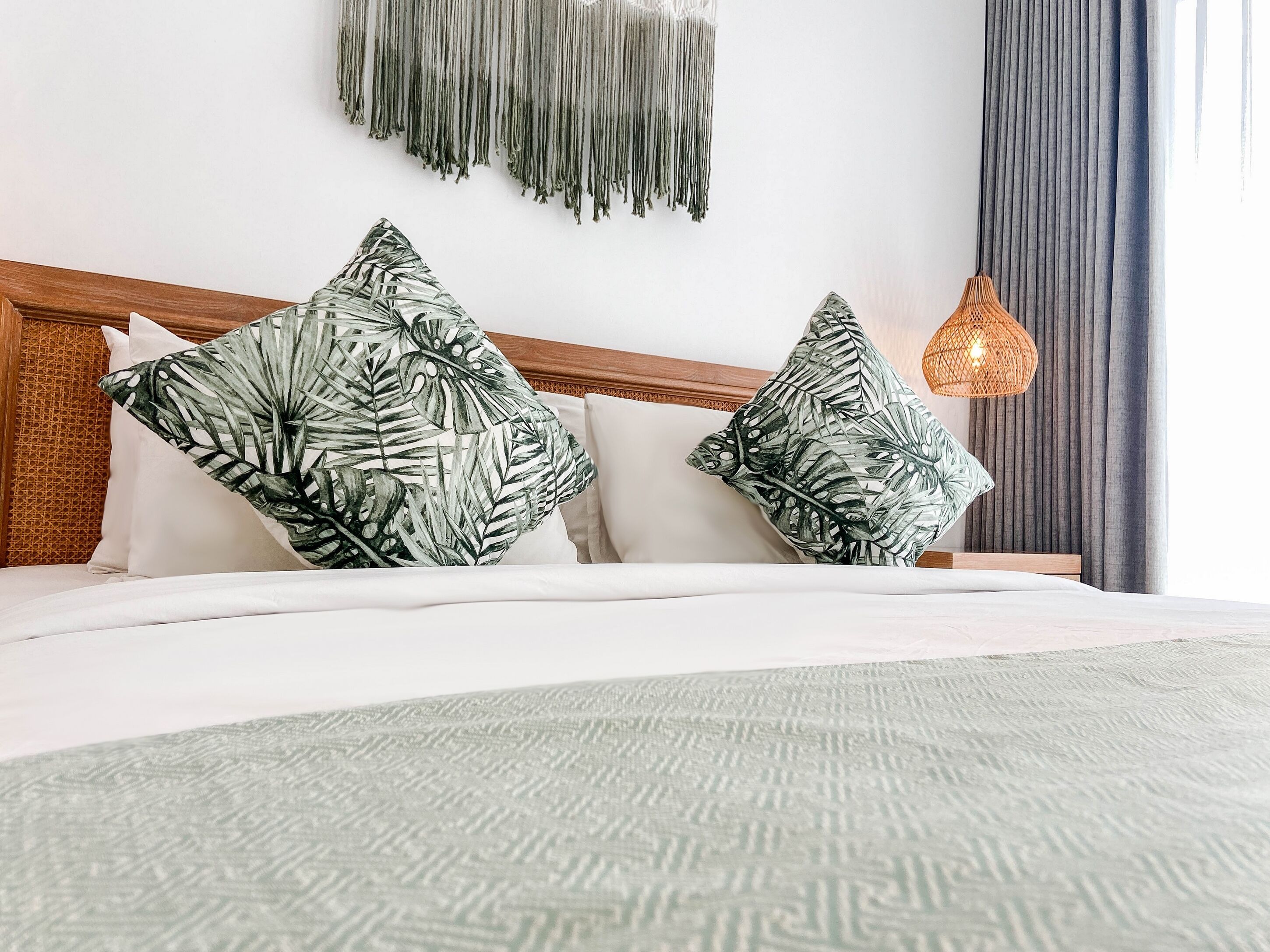 Una cama bien hecha con una colcha estampada y dos almohadas decorativas.