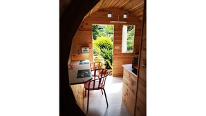 Un intérieur en bois comprenant un coin cuisine, une table à manger avec des chaises et une vue sur la verdure à l’extérieur.