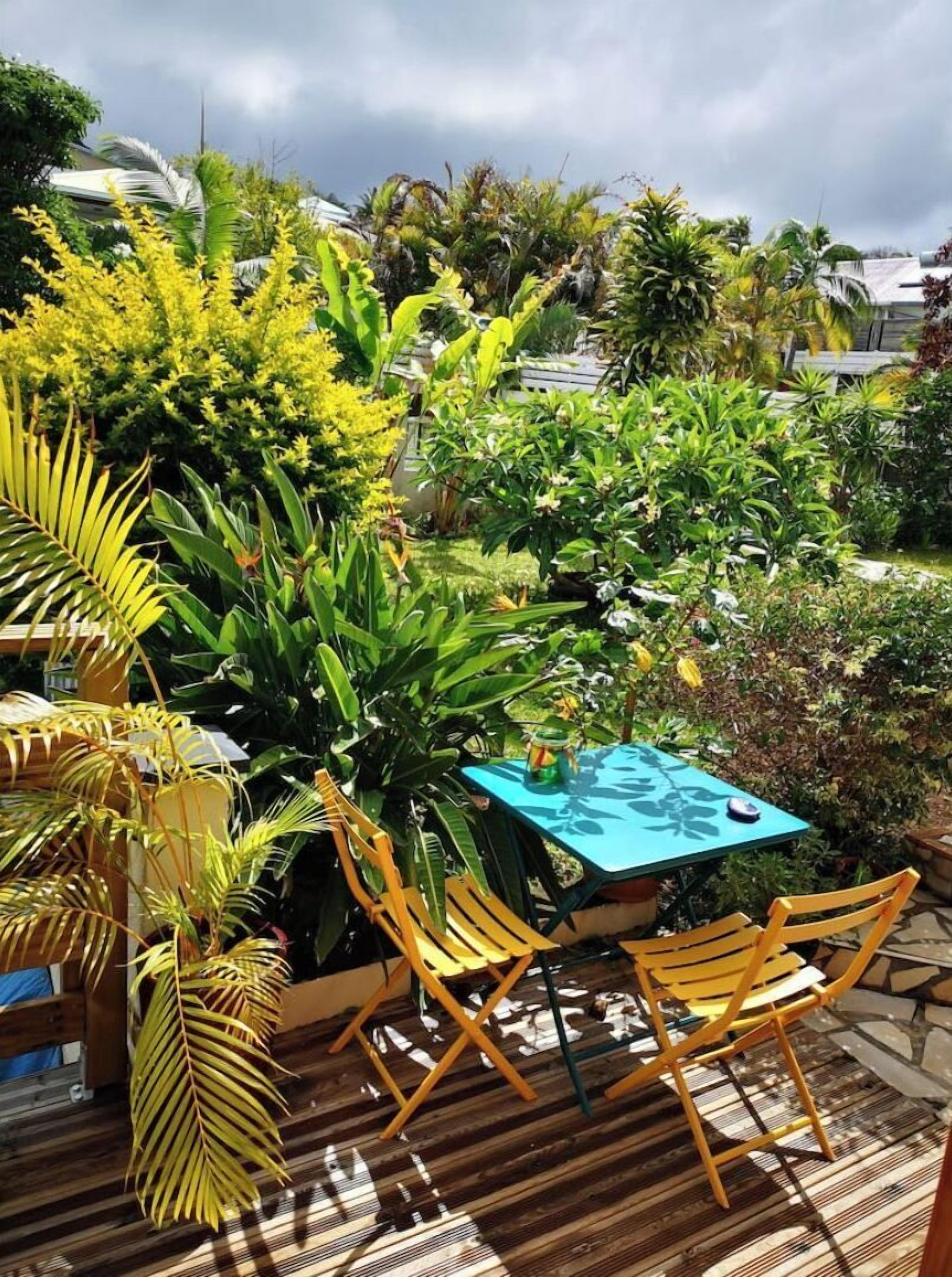 An outdoor patio with a table and chairs, surrounded by lush tropical plants.