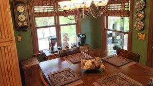 A dining area with a wooden table, woven placemats, a chandelier, and a coffee maker. - Cozy Bear Paradise  on Weiss Lake  in the foothills of the Appalachian Mountains (Cedar Bluff)