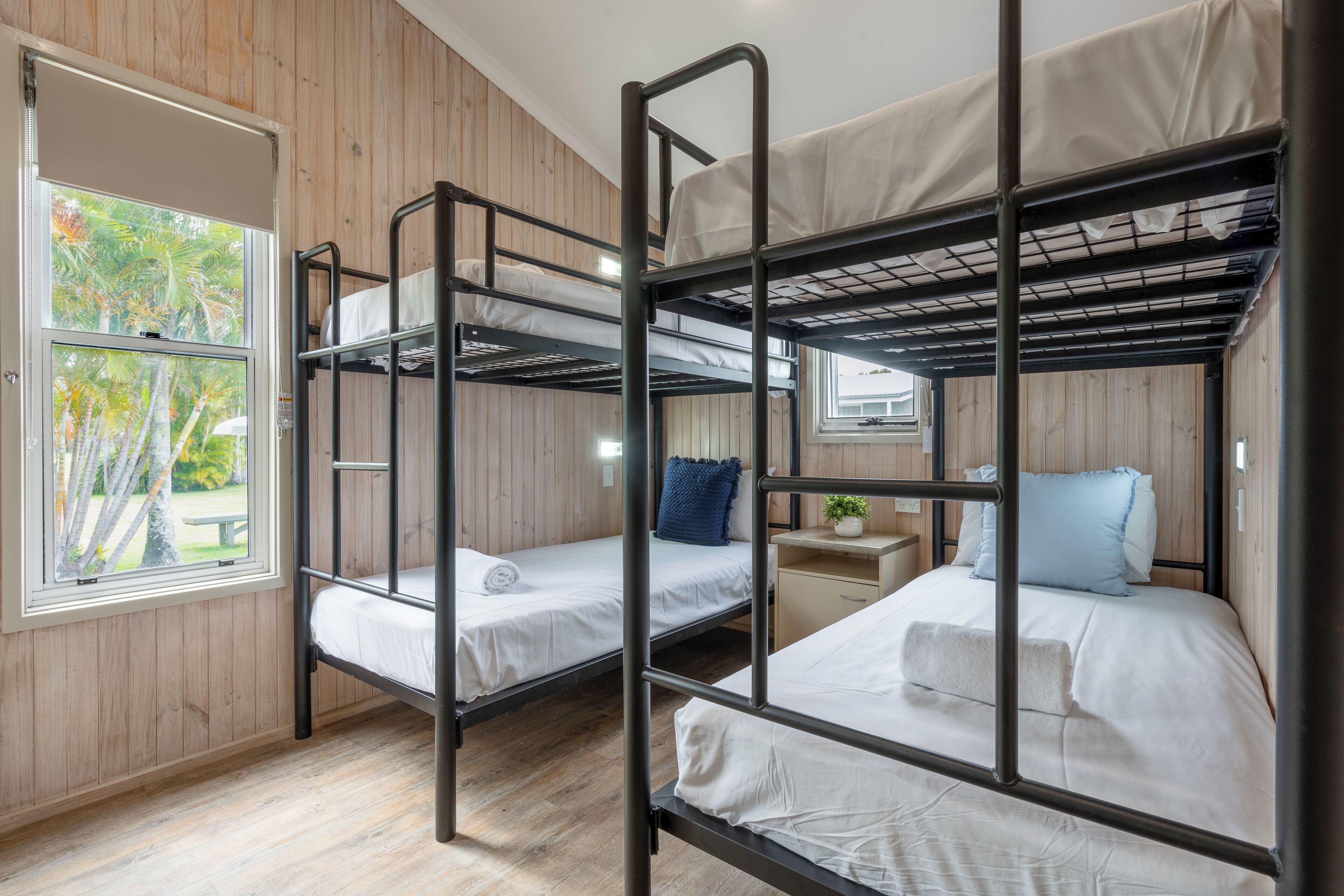 A bunk bed room with wooden walls and a window.