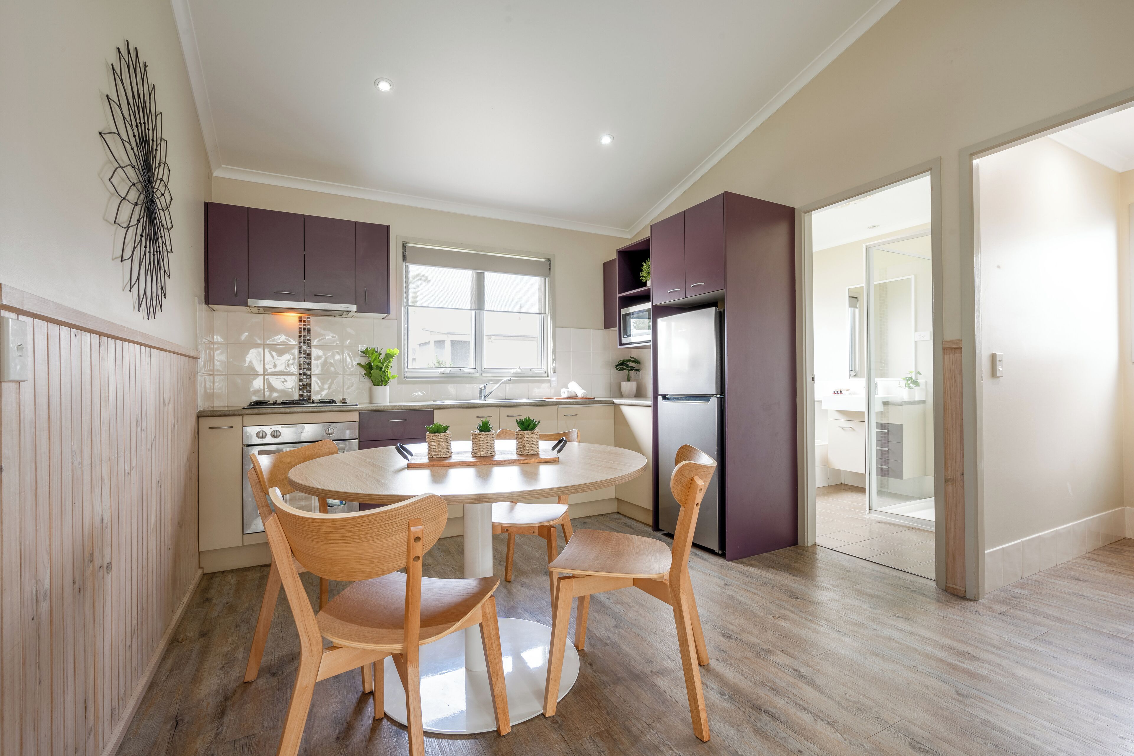 A modern kitchen with wooden cabinets, a round dining table, and chairs.